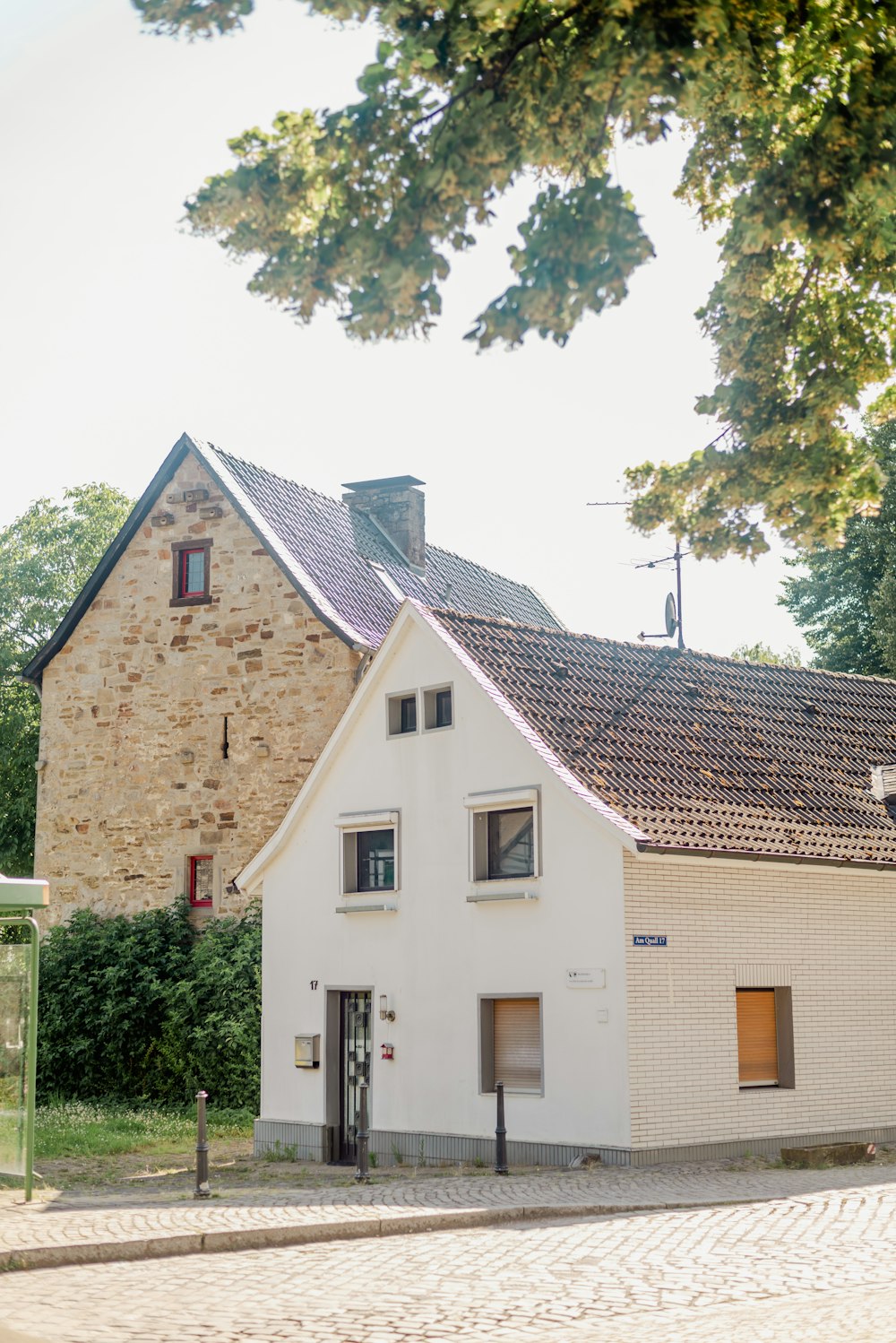 a white house with a brown roof and a tree in front of it