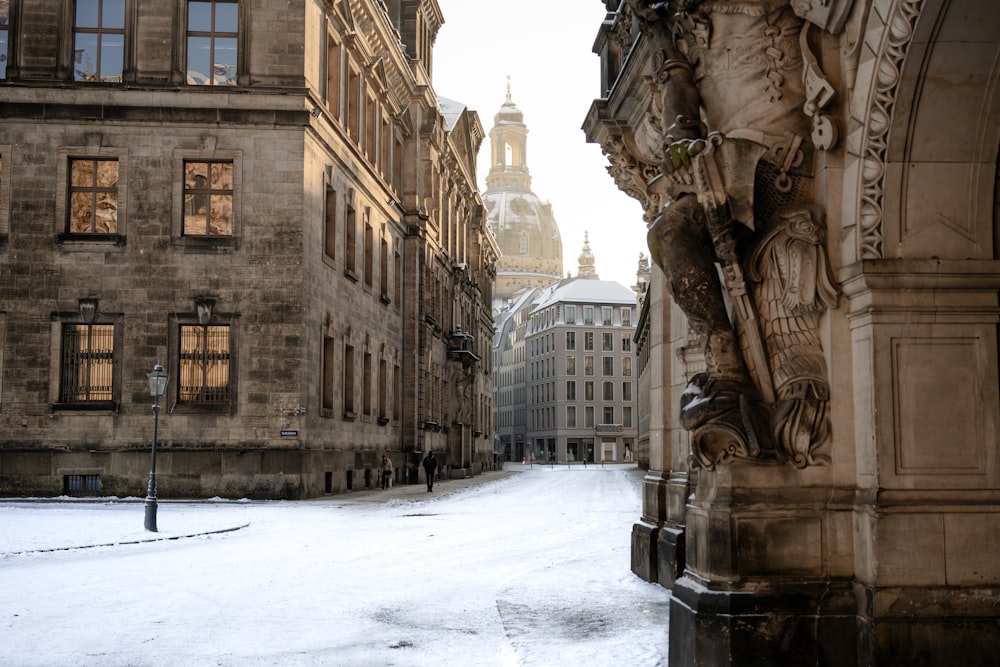 a snowy street with buildings and a clock tower in the background