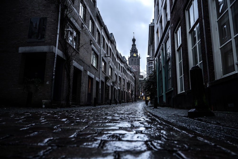 a dark street with a clock tower in the distance