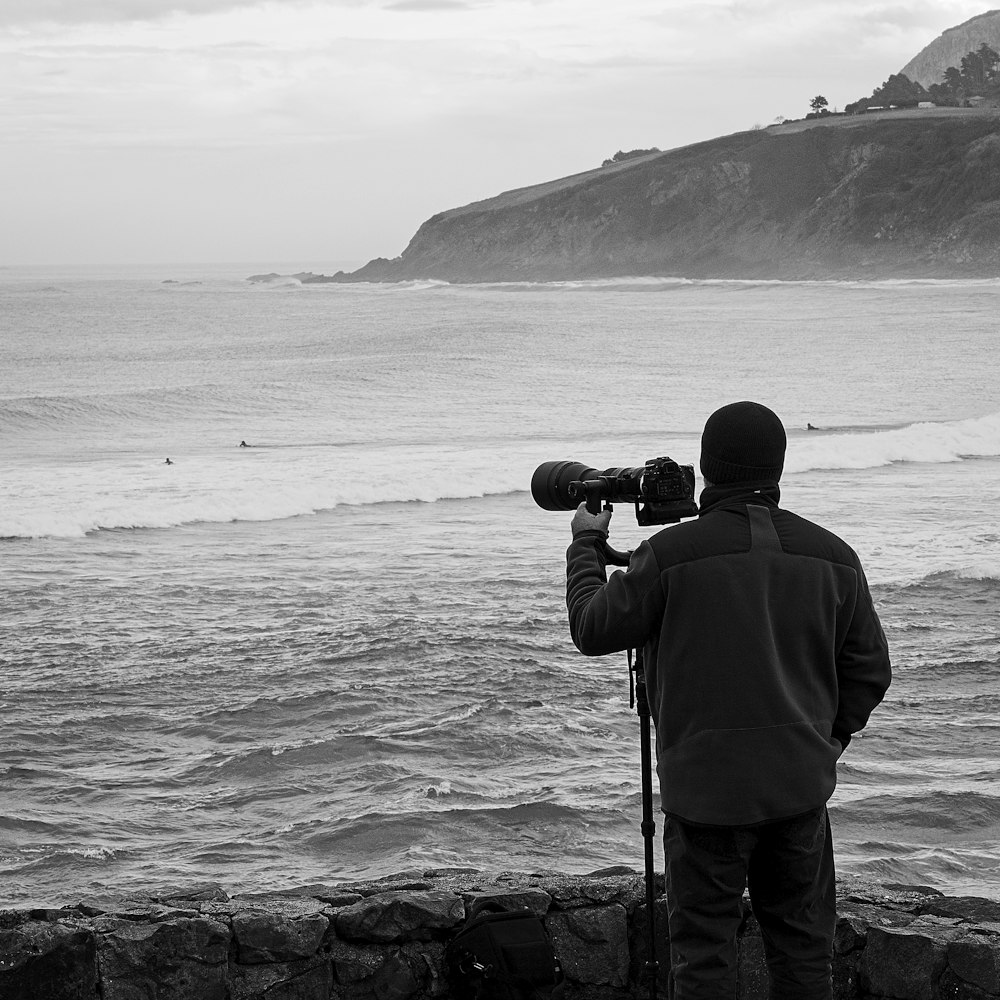 a man standing on top of a beach next to the ocean