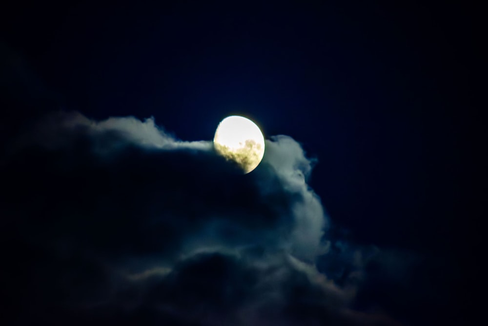 a full moon is seen through the clouds