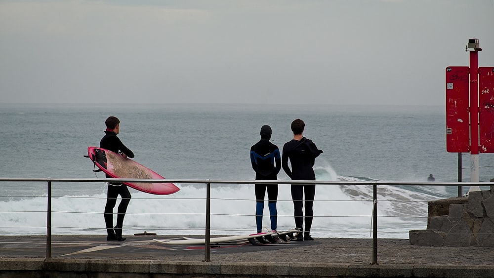 a group of people standing on top of a pier next to the ocean