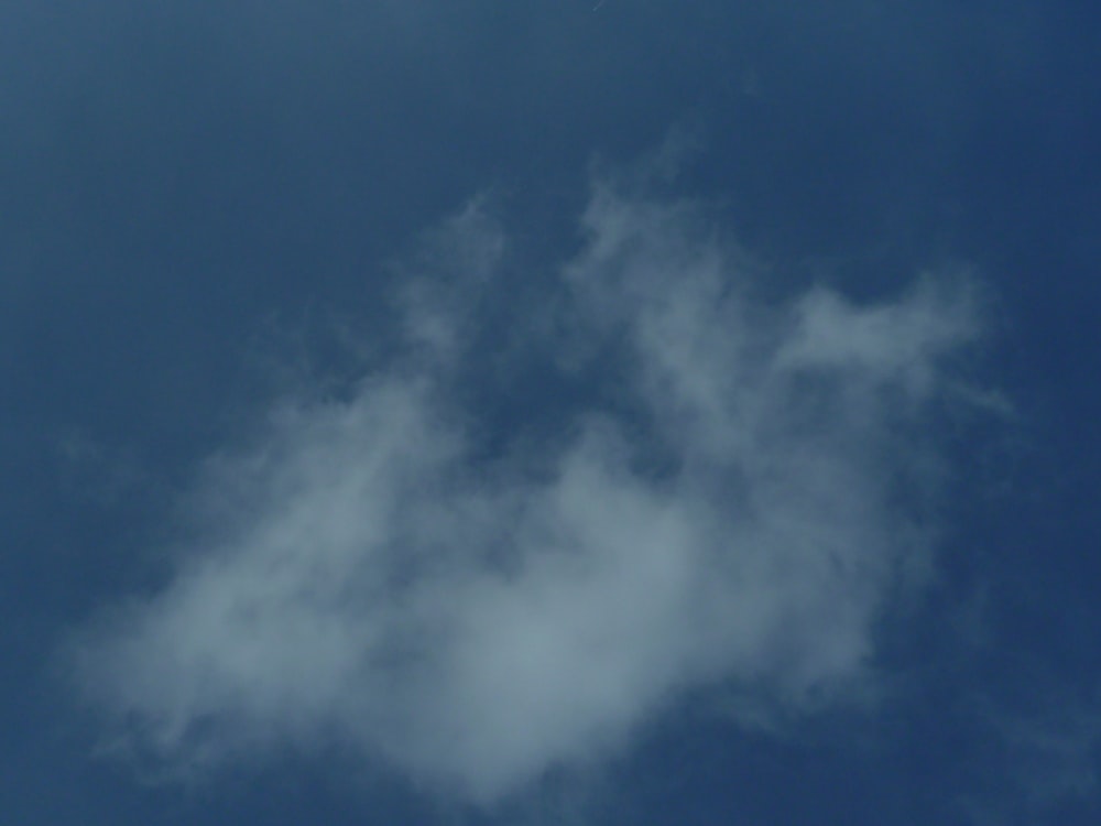 a plane flying through a cloudy blue sky