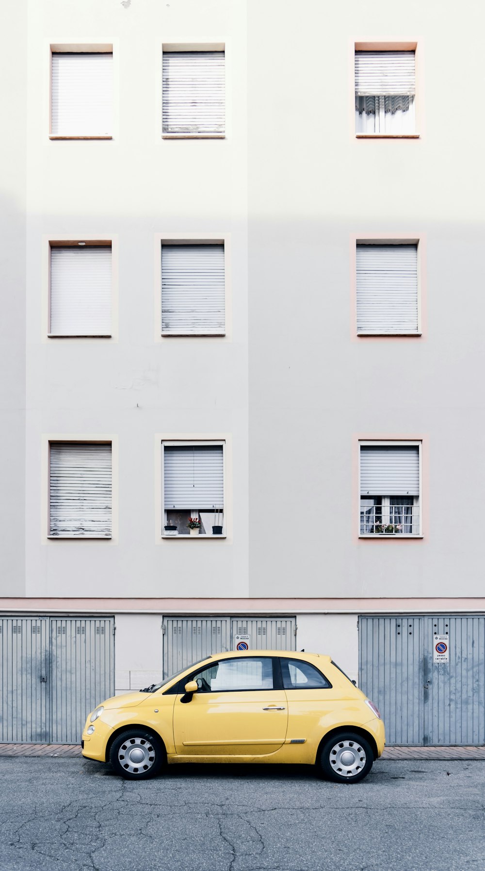 a yellow car parked in front of a tall building