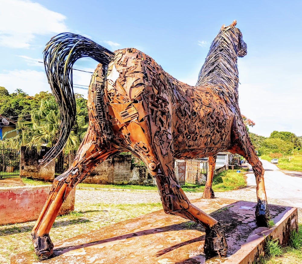 a large wooden horse standing on top of a lush green field