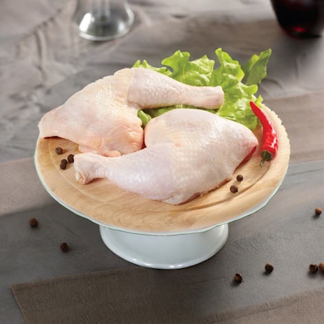 two raw chickens on a plate with lettuce and pepper