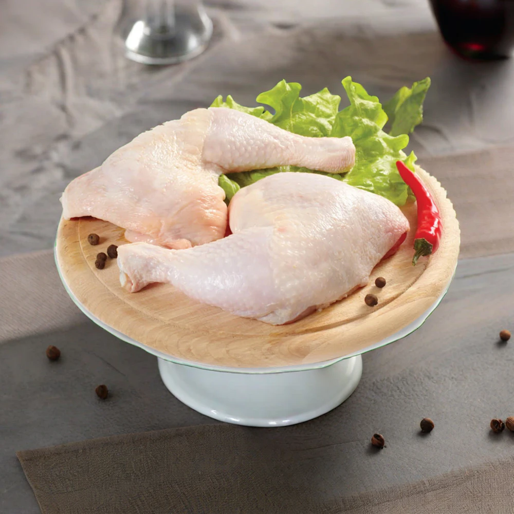 Two raw chicken leg quarters on a wooden serving stand
