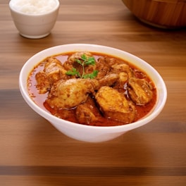 a bowl of chicken curry next to a bowl of rice