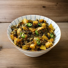 a white bowl filled with food on top of a wooden table