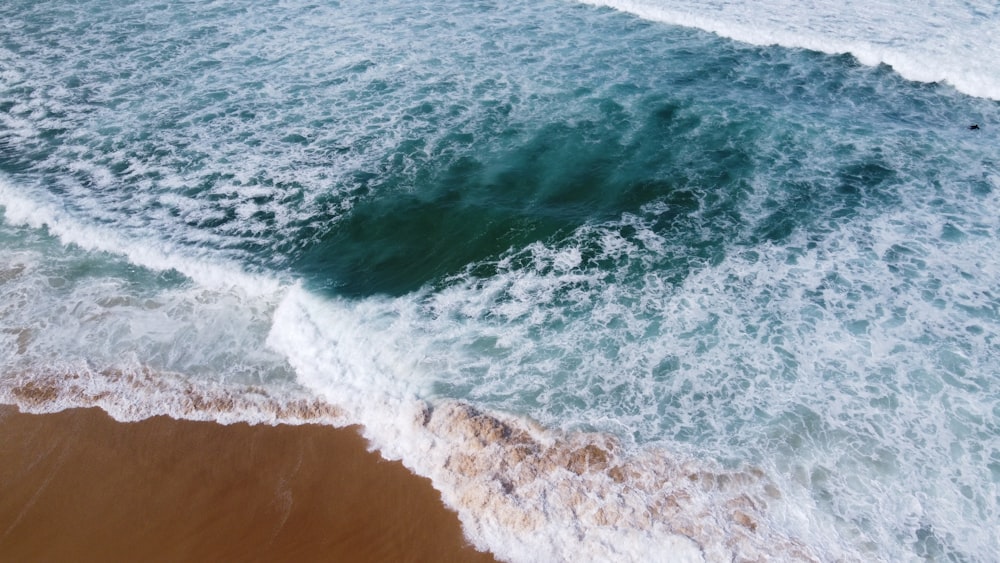 an aerial view of a beach with waves coming in