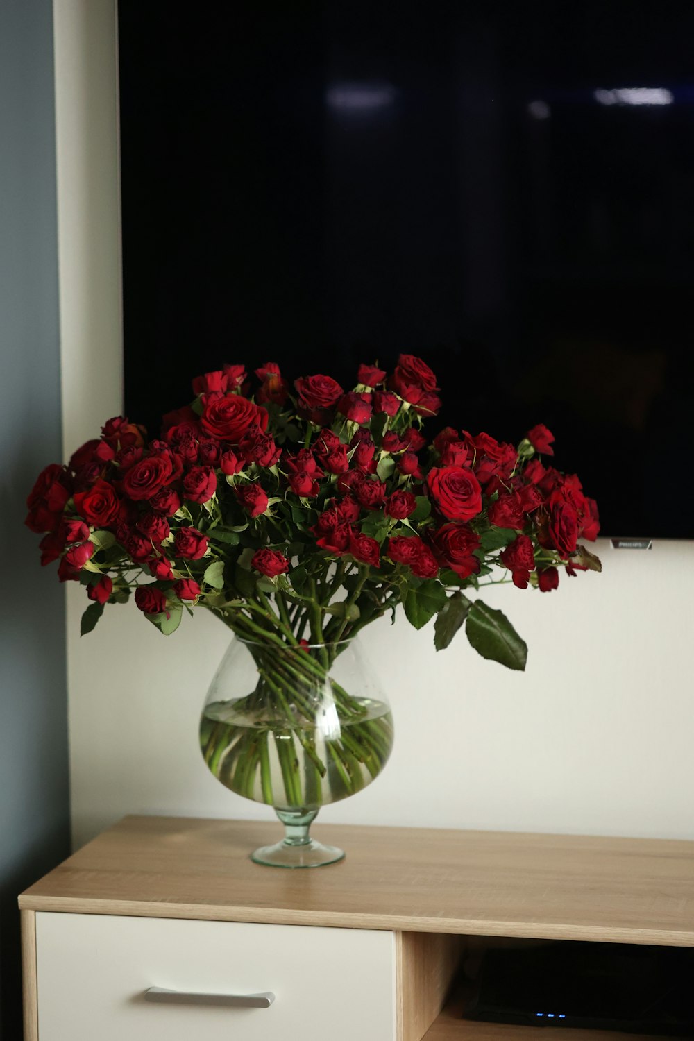 un vaso pieno di rose rosse seduto sopra un tavolo