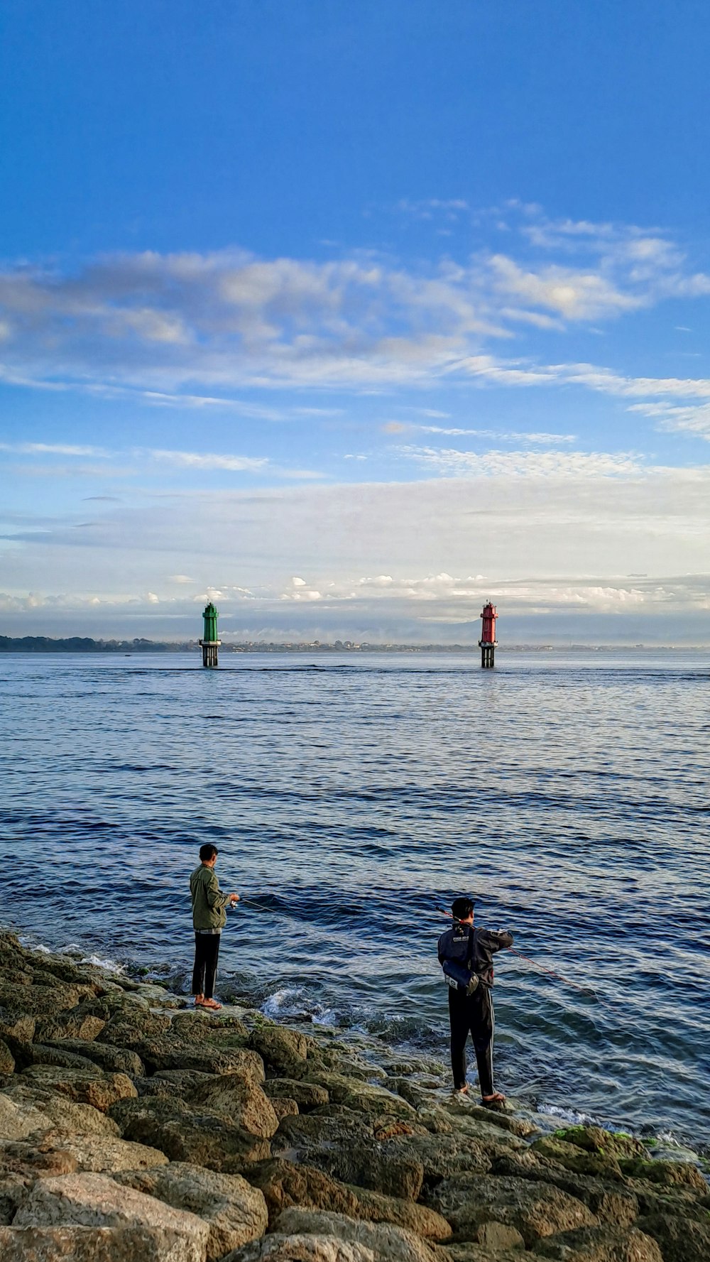 a couple of people standing on top of a rocky beach