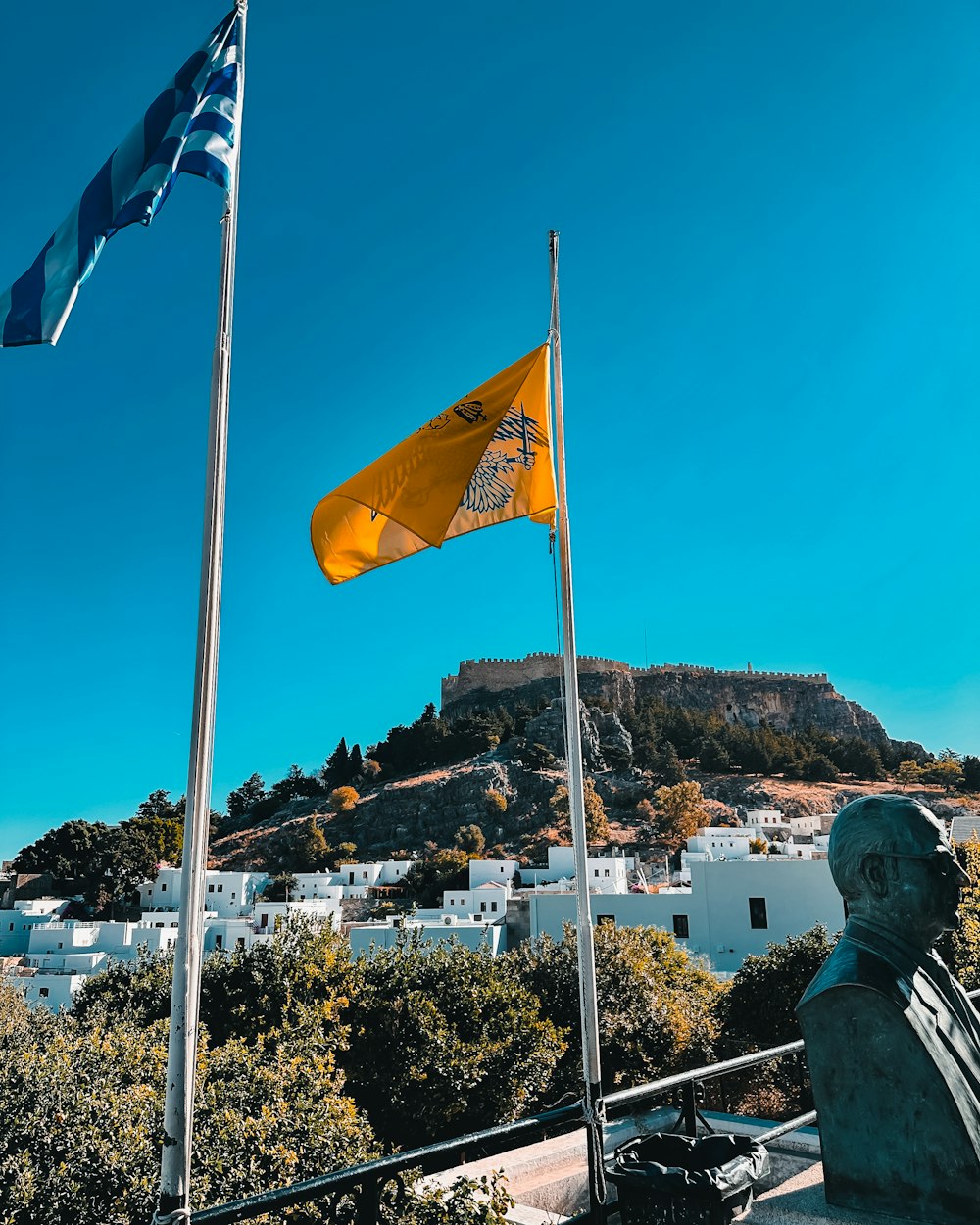 une statue avec un drapeau jaune au sommet d’une colline