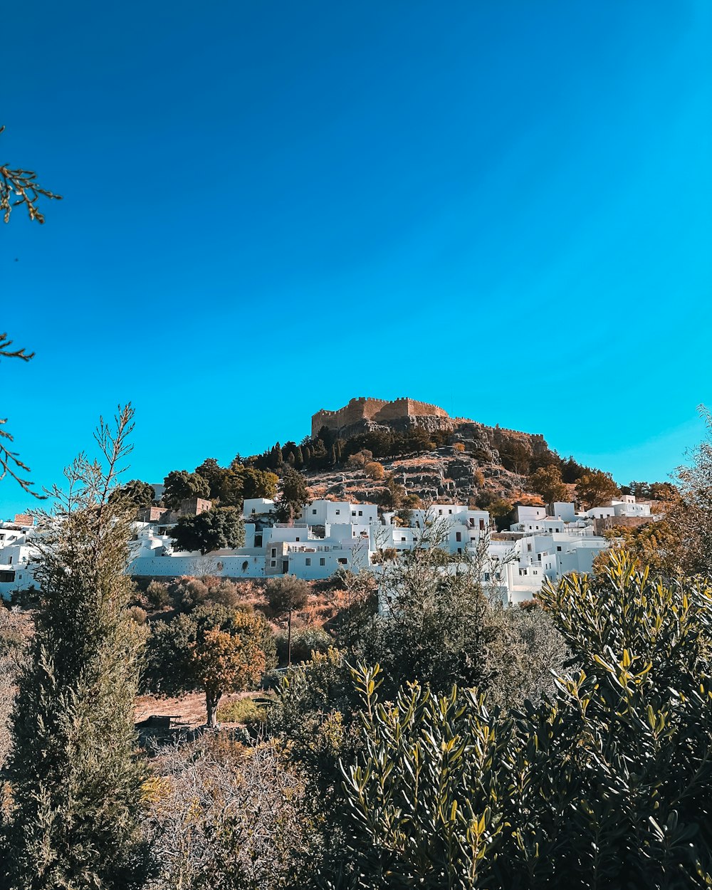a white village on top of a hill surrounded by trees