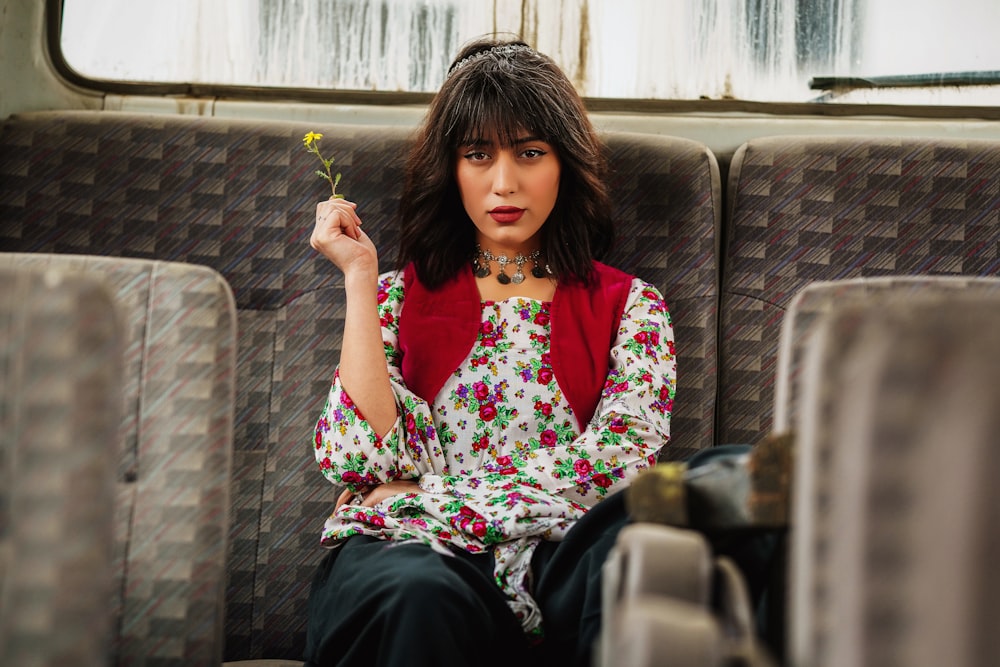a woman sitting on a train holding a flower