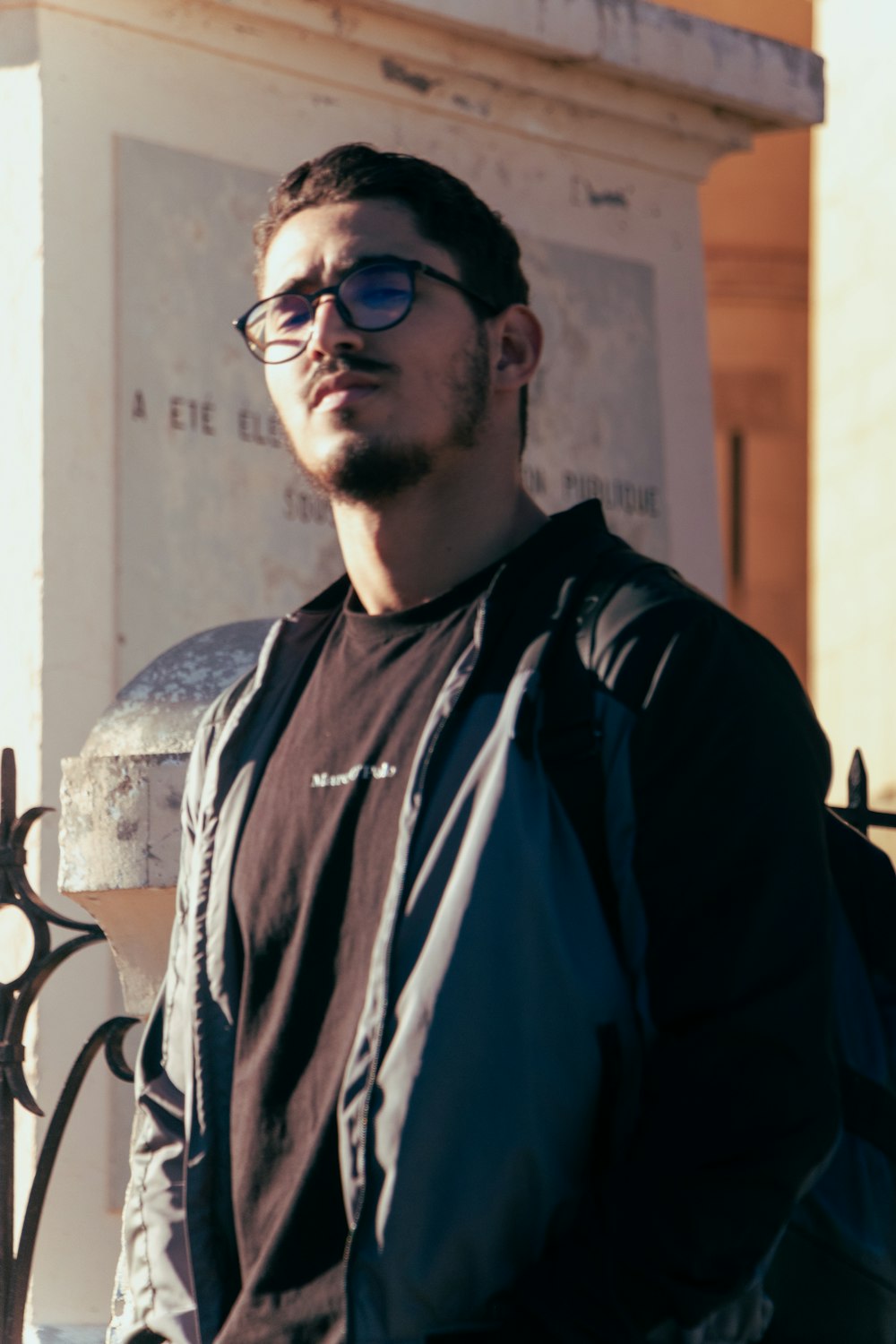 a man with glasses standing in front of a building