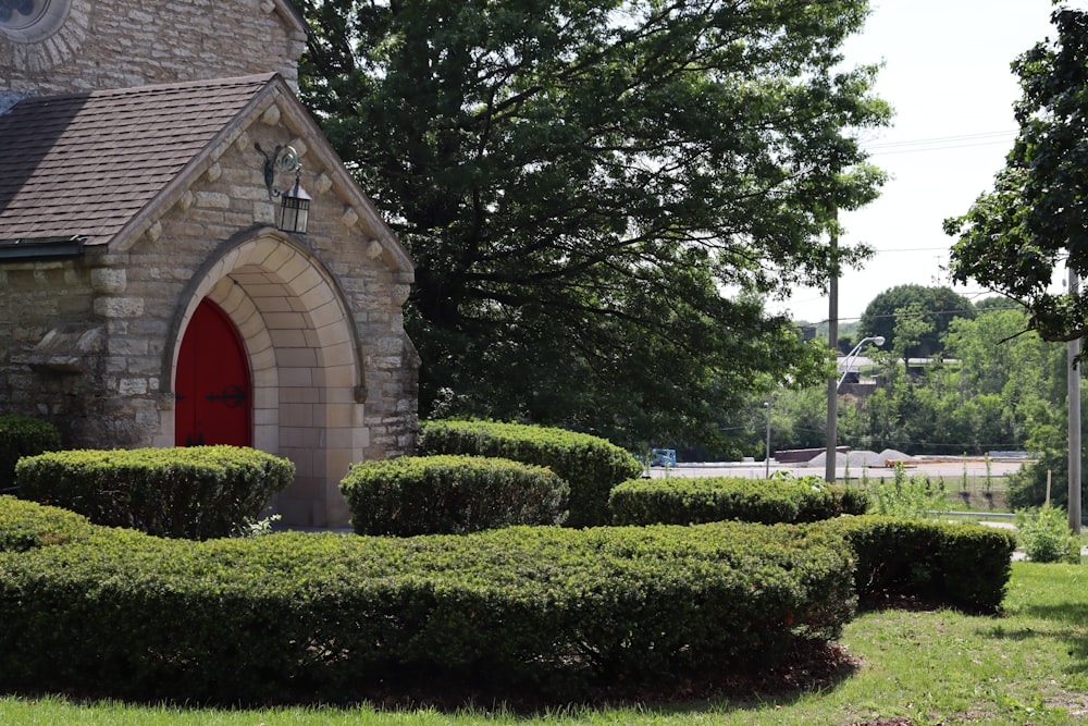 a church with a red door surrounded by hedges