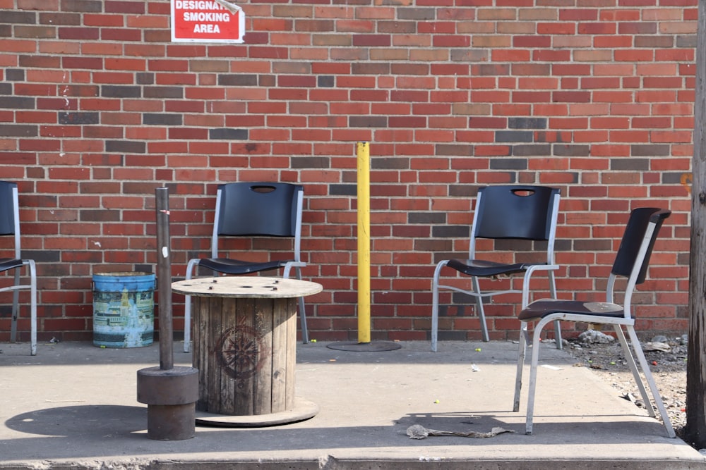 three chairs and a fire hydrant in front of a brick wall