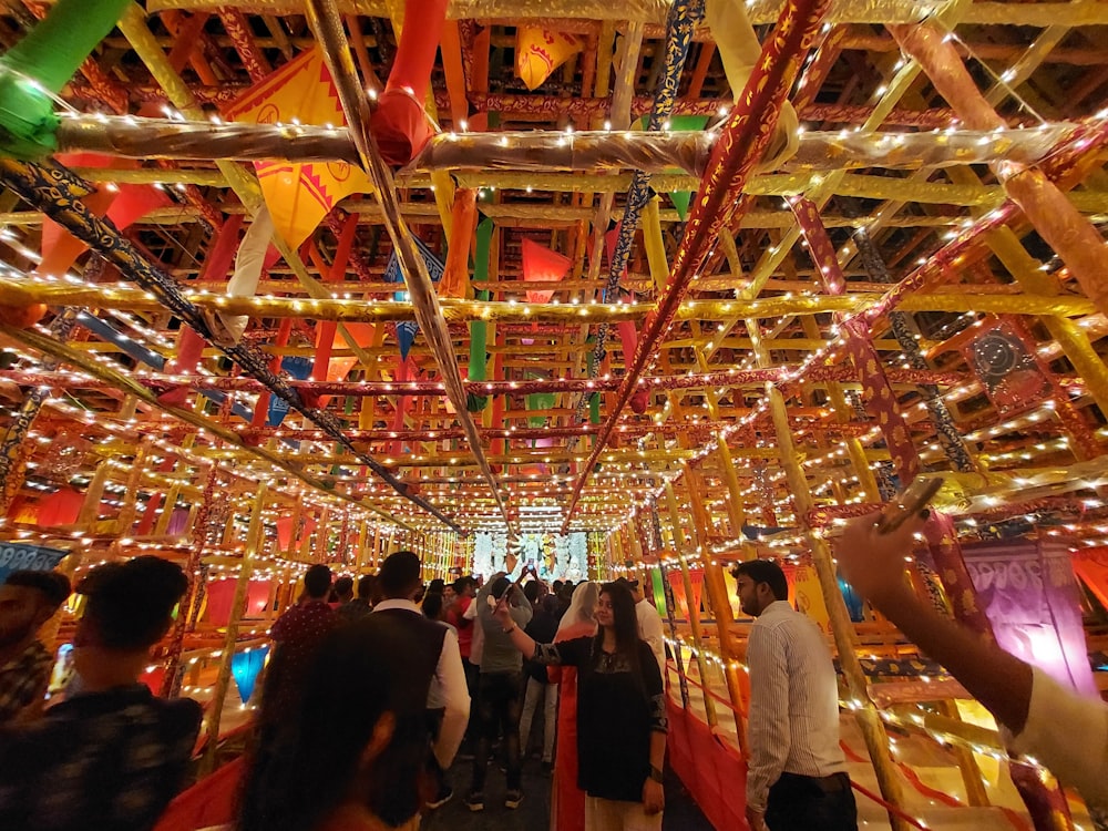 a group of people walking down a hallway covered in lights