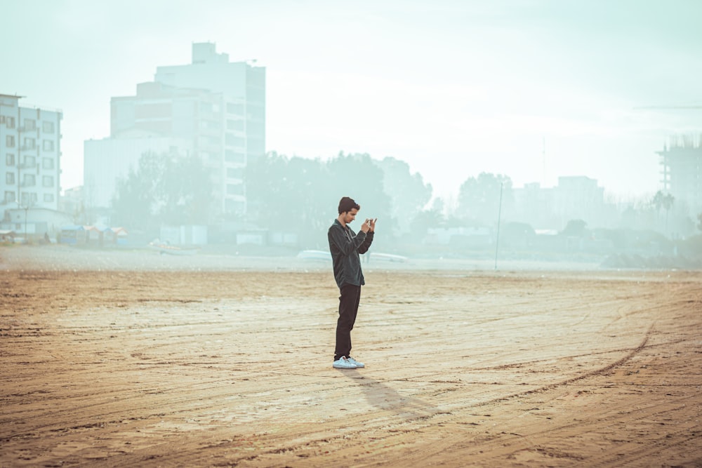 a man standing in the middle of a dirt field