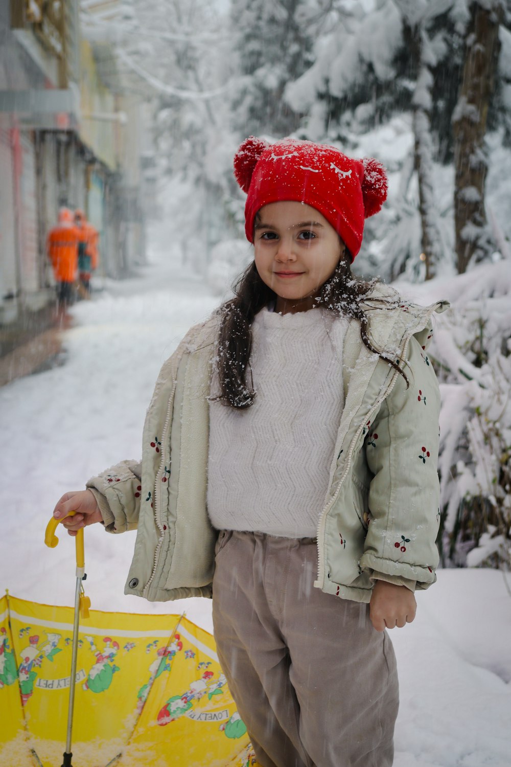 a little girl standing in the snow holding an umbrella