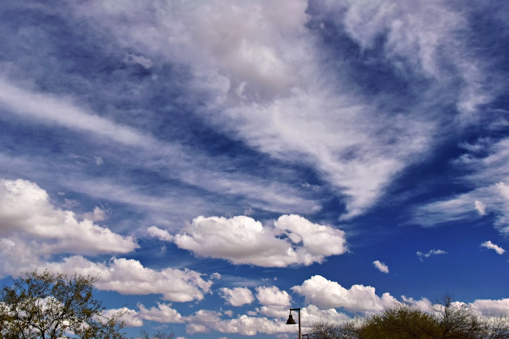 a blue sky with white clouds and a street light