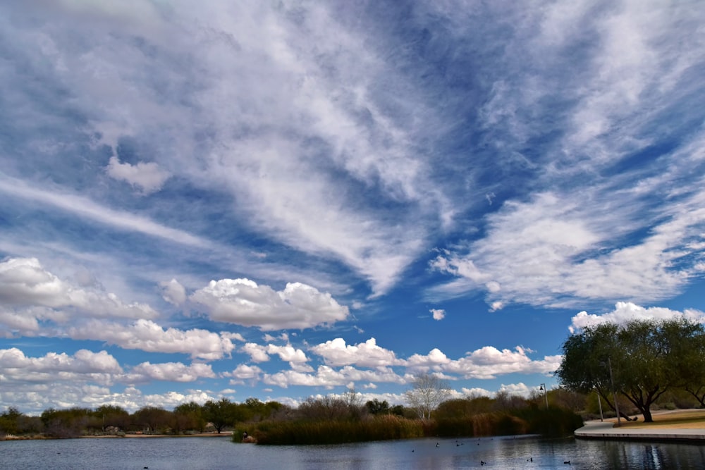 a body of water surrounded by trees and clouds