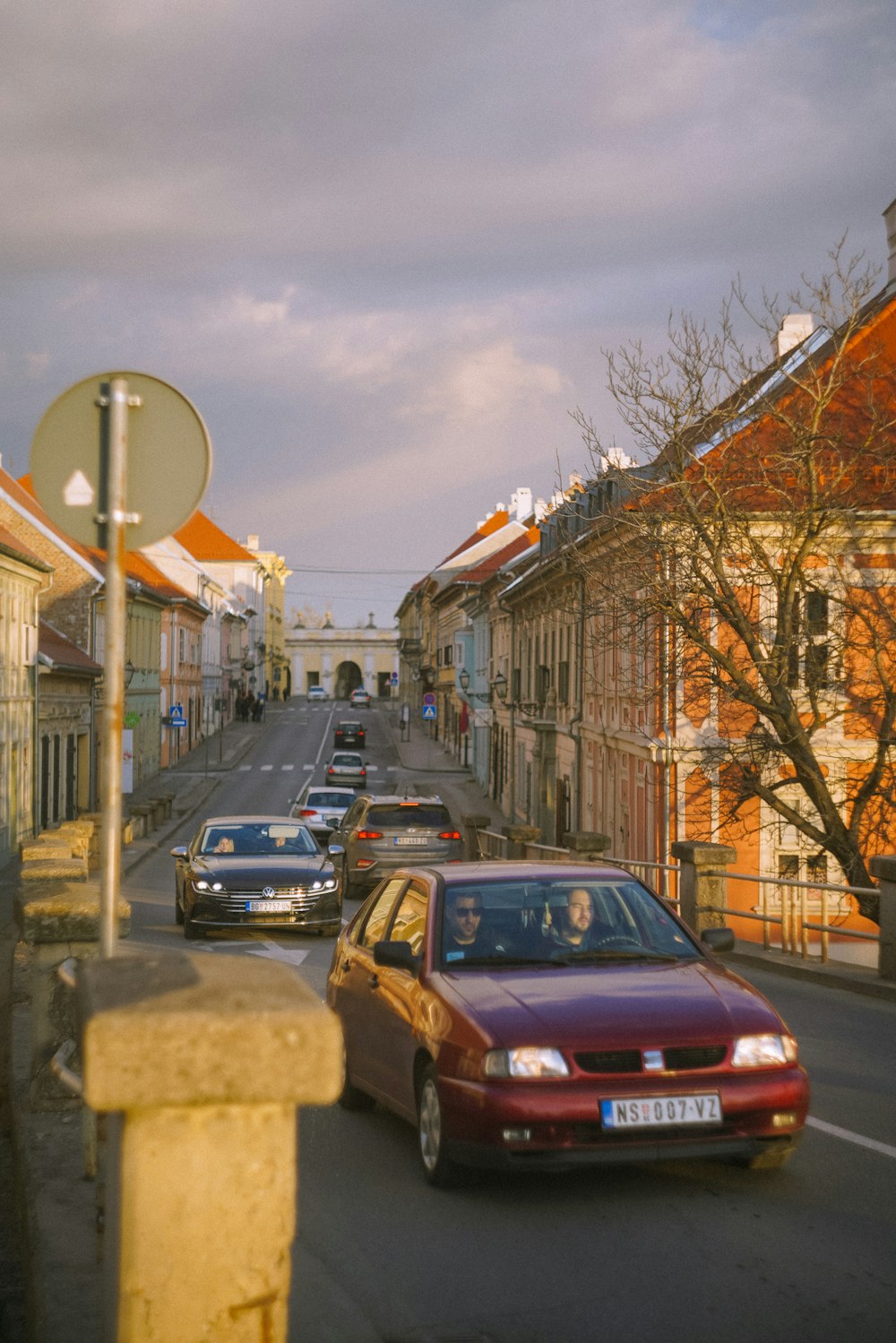 a red car driving down a street next to tall buildings