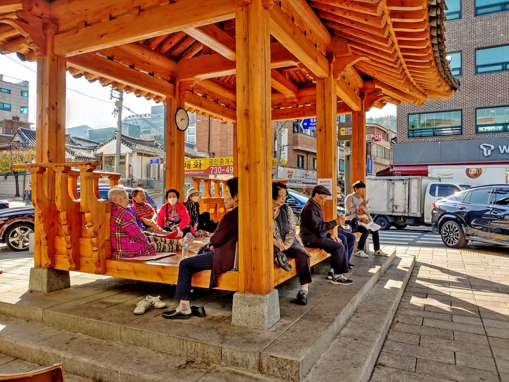 a group of people sitting under a wooden structure
