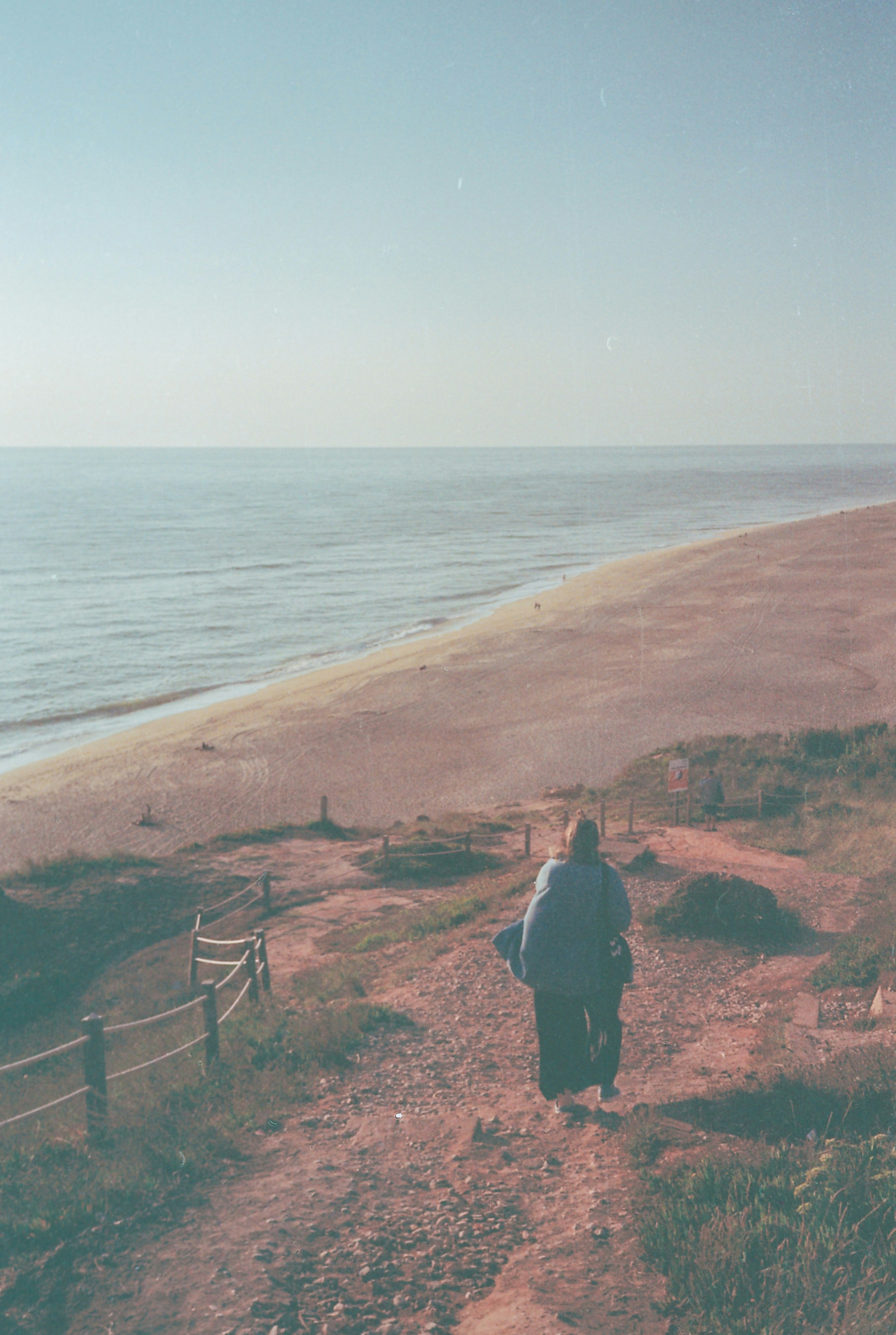 a person walking down a path near the beach