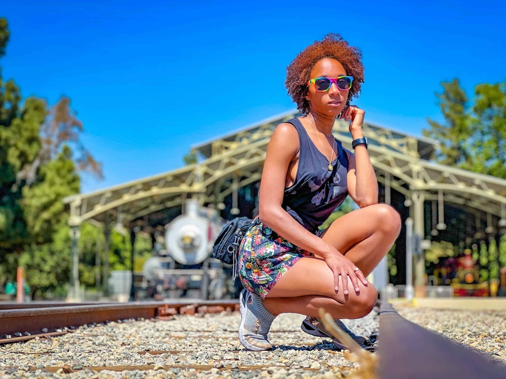a woman sitting on a train track with her hand on her chin