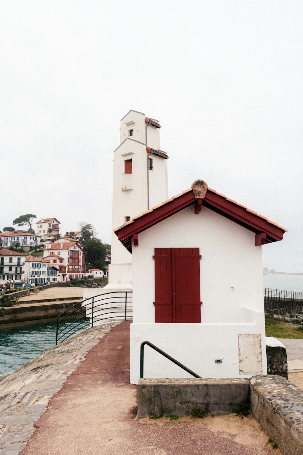 a white building with a red door next to a body of water