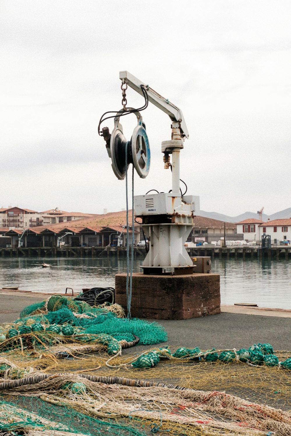 a crane sitting on top of a pile of rope next to a body of water