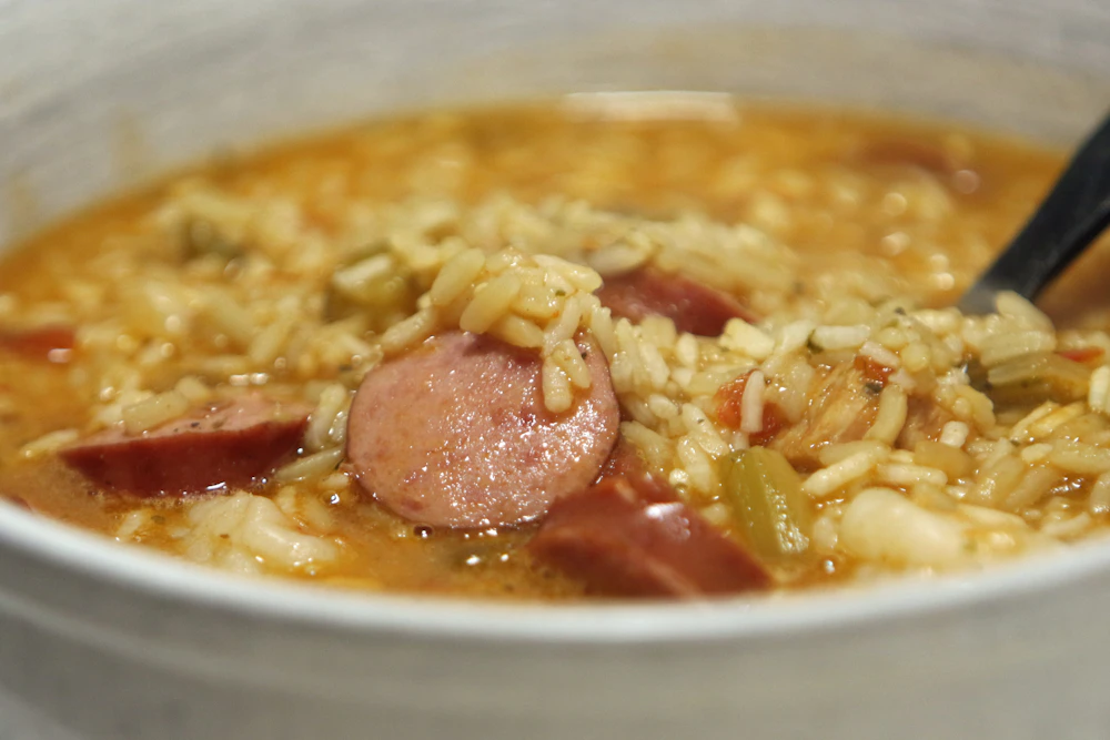A close view of jambalaya with rice and rounds of smoked sausage in a bowl