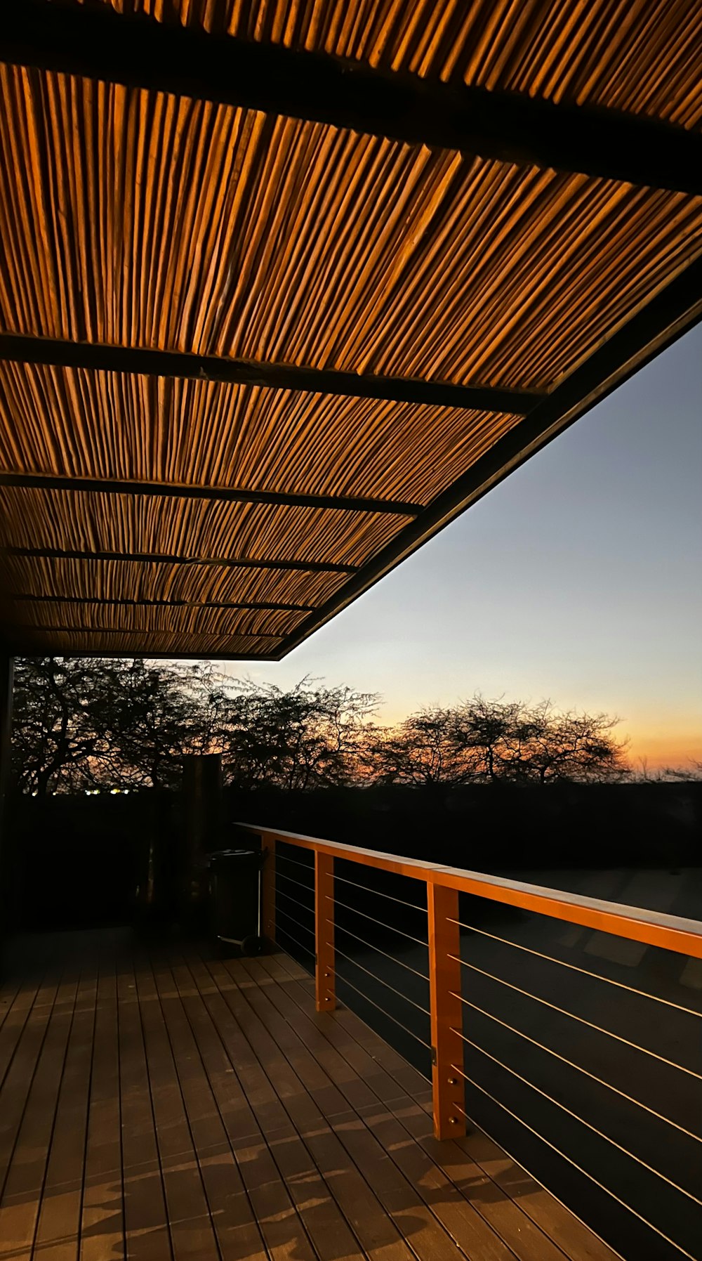 a wooden deck with a railing and a view of the sunset