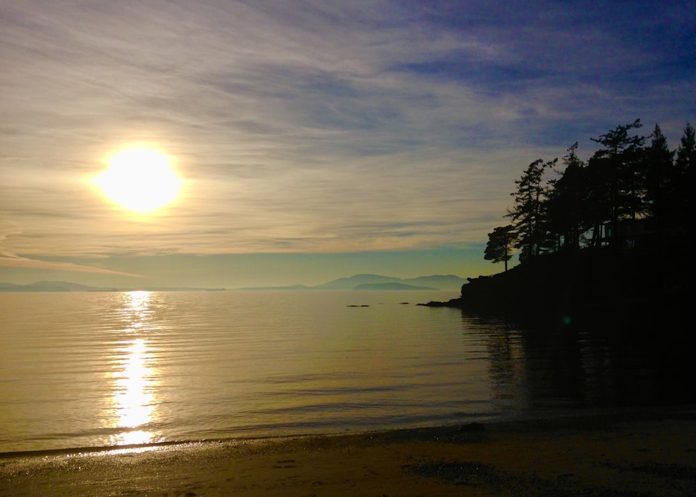 the sun is setting over the water at the beach