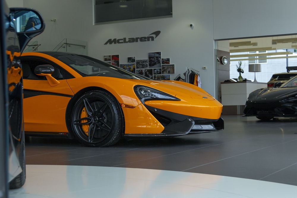 an orange sports car parked in a showroom