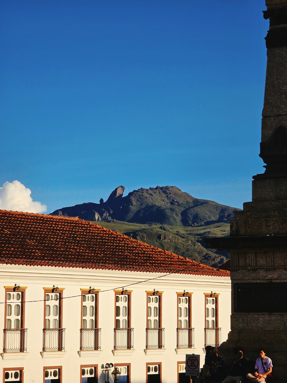 a building with a clock tower and a mountain in the background