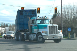 a blue dump truck driving down a street