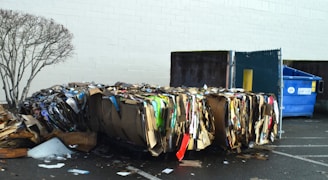 a pile of trash sitting next to a blue trash can