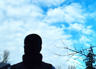 a man standing in front of a blue sky with clouds
