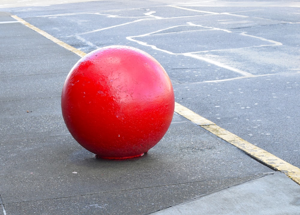 a large red ball sitting on the side of a road