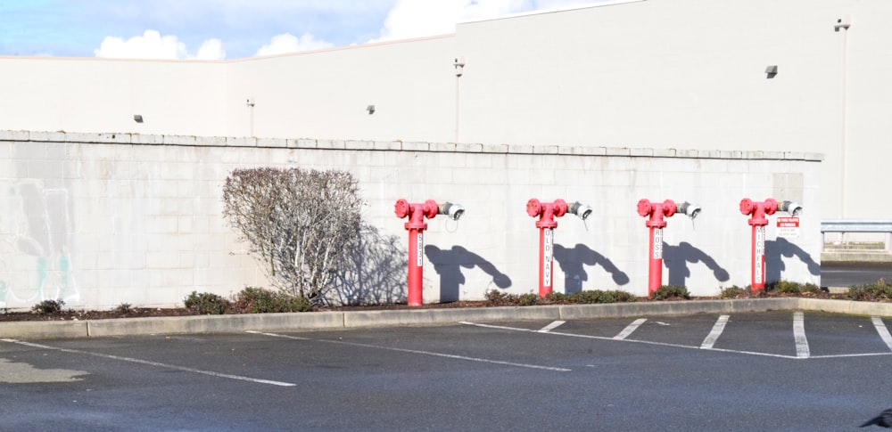 a row of red fire hydrants in a parking lot
