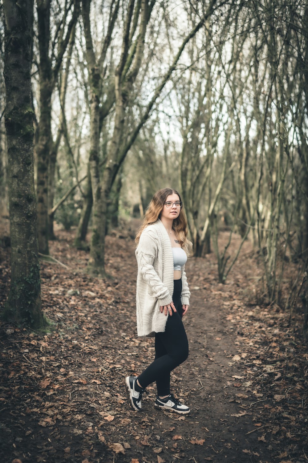 a woman is walking through a wooded area