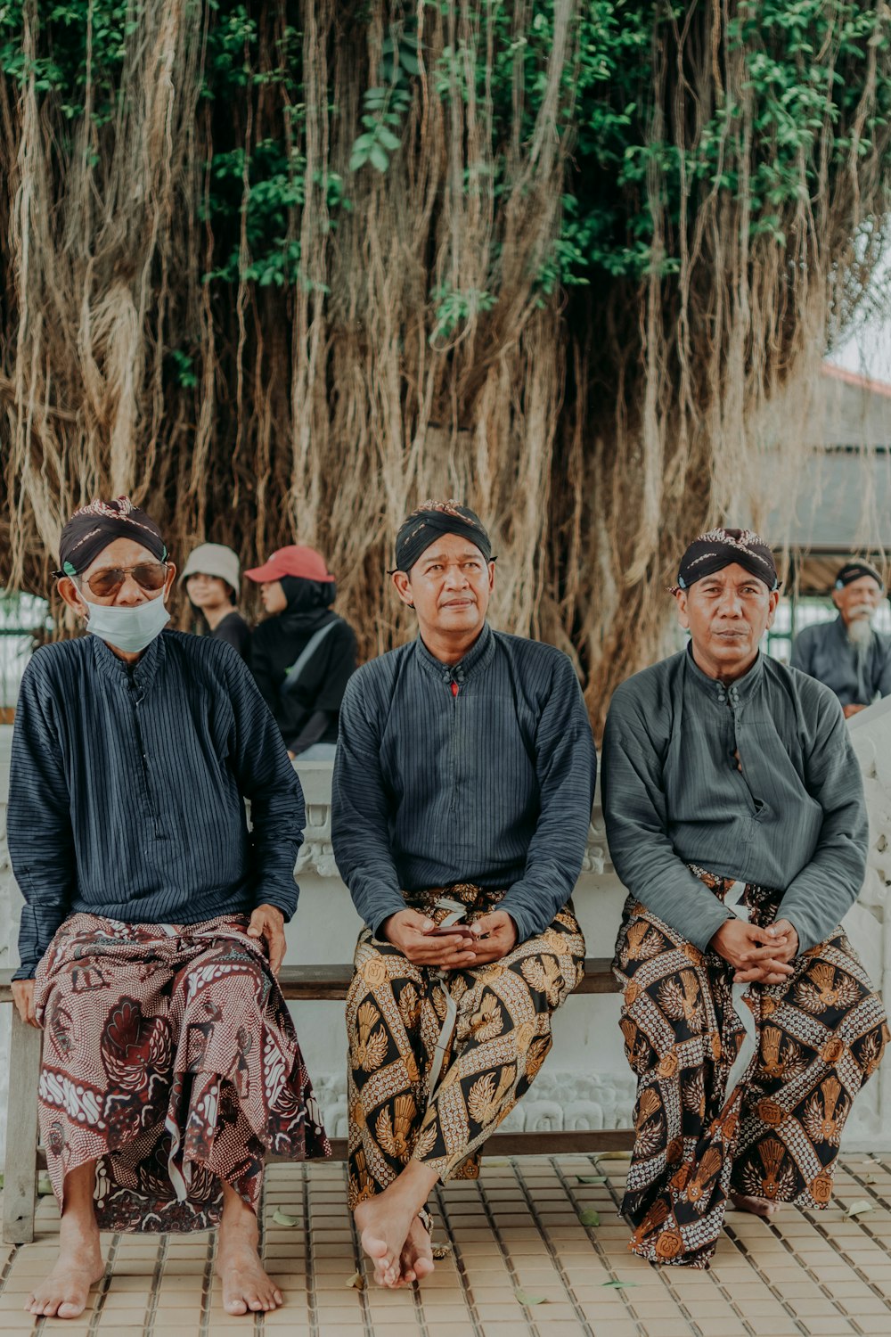 a group of people sitting on a bench under a tree