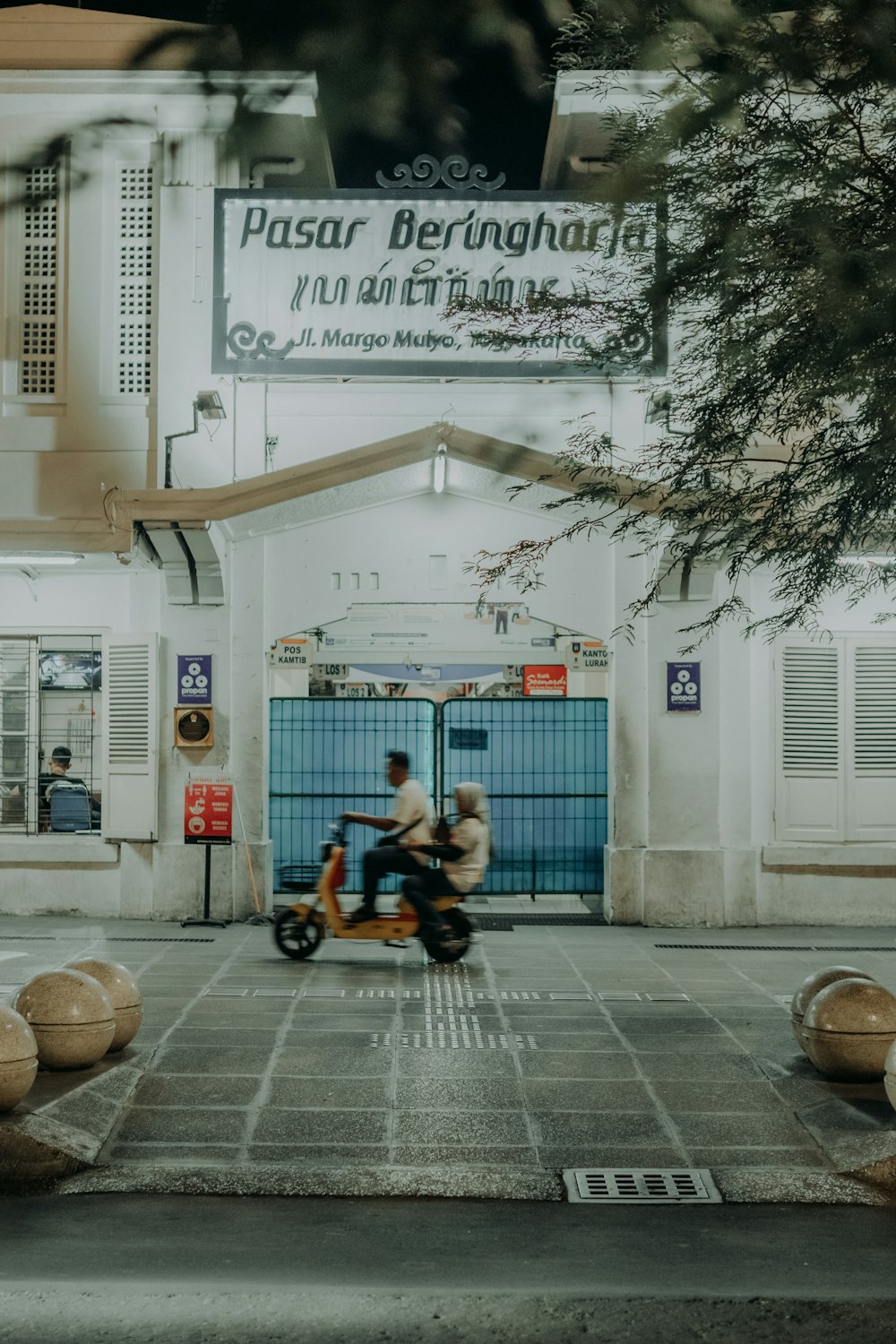 two people riding a scooter in front of a building