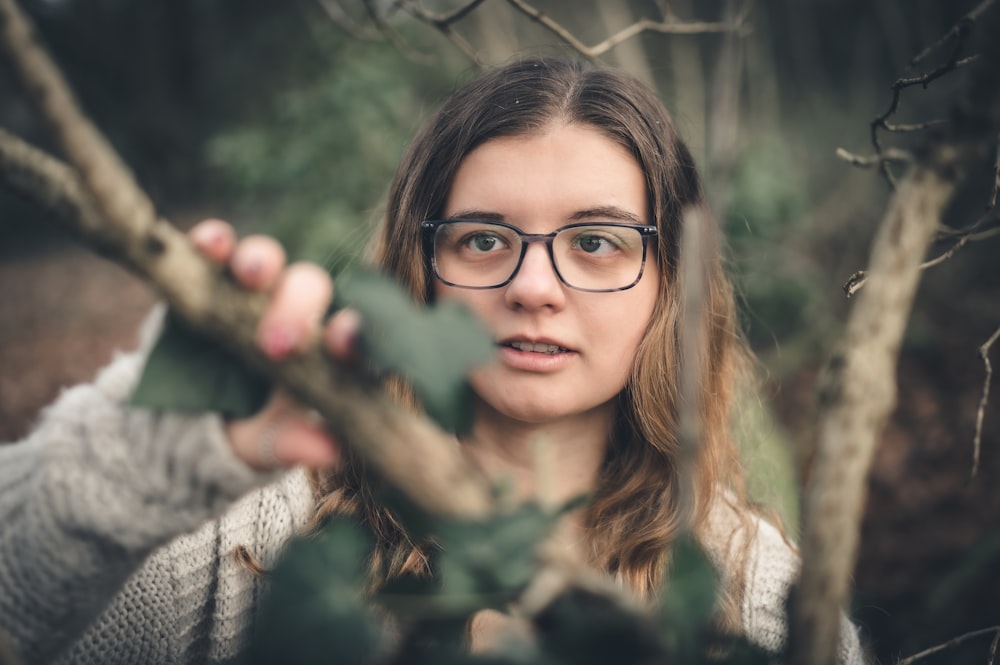 a woman wearing glasses is holding a branch