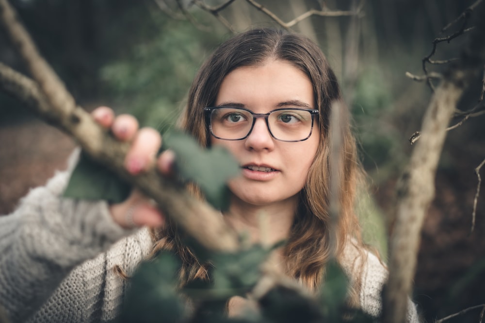 Une femme portant des lunettes tient une branche