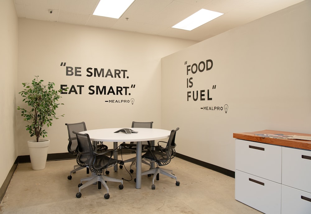 an office with a white table and black chairs