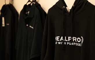 a row of black sweatshirts hanging on a wall